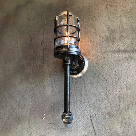 an old industrial style wall lamp with a metal cage and glass globe mounted on a concrete wall